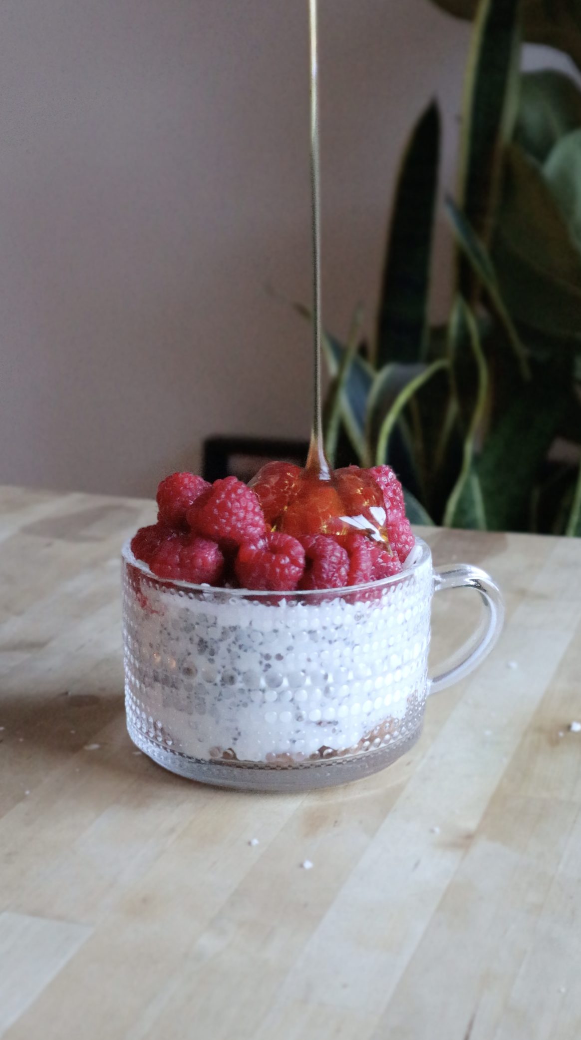 Honey being poured over a chia seed parfait topped with raspberries