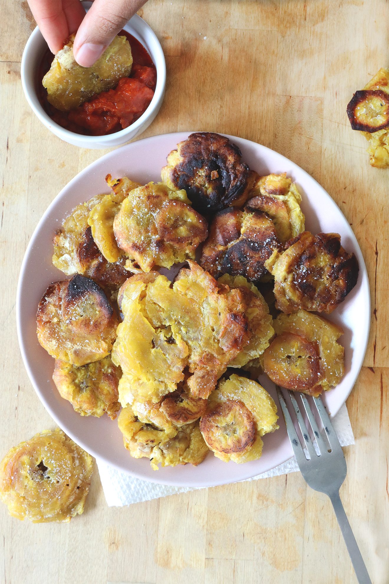 Plate of golden fried tostones with a dipping sauce